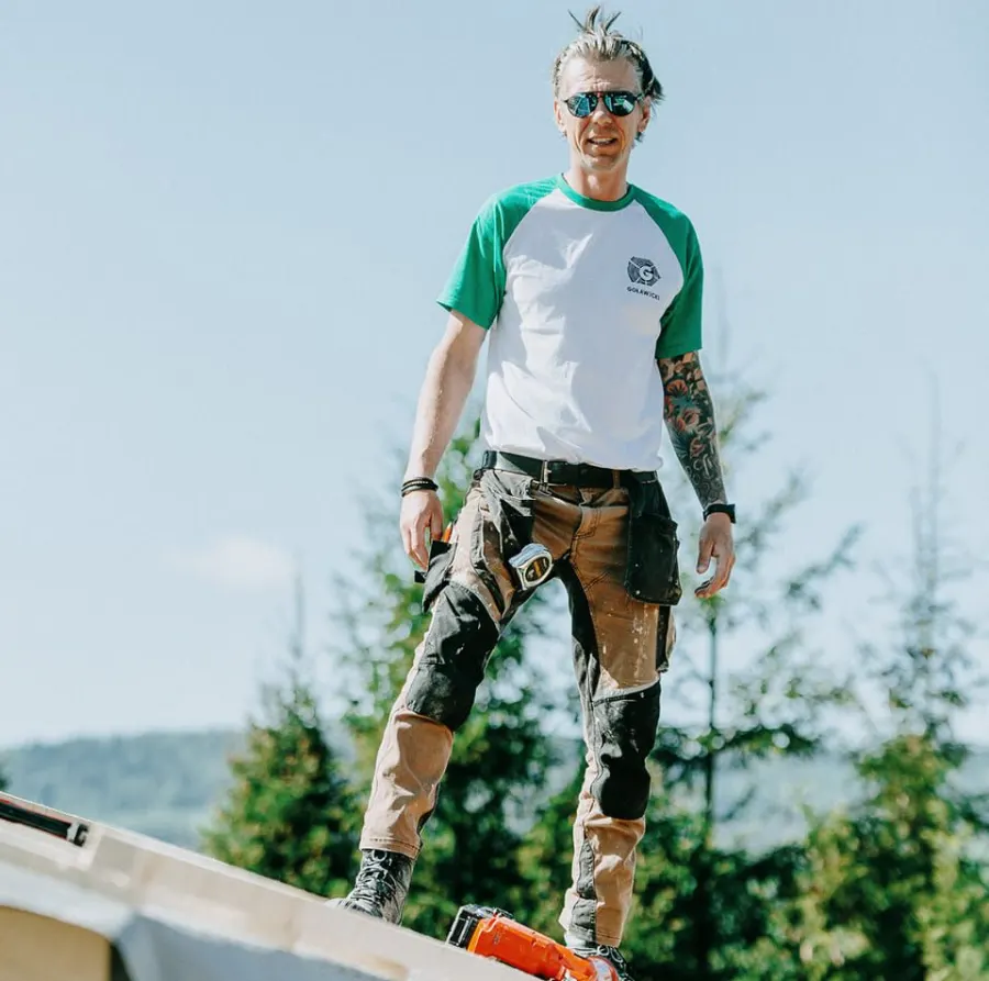 Wykonawca na dachu budowanego domu, w tle las i wzgórza